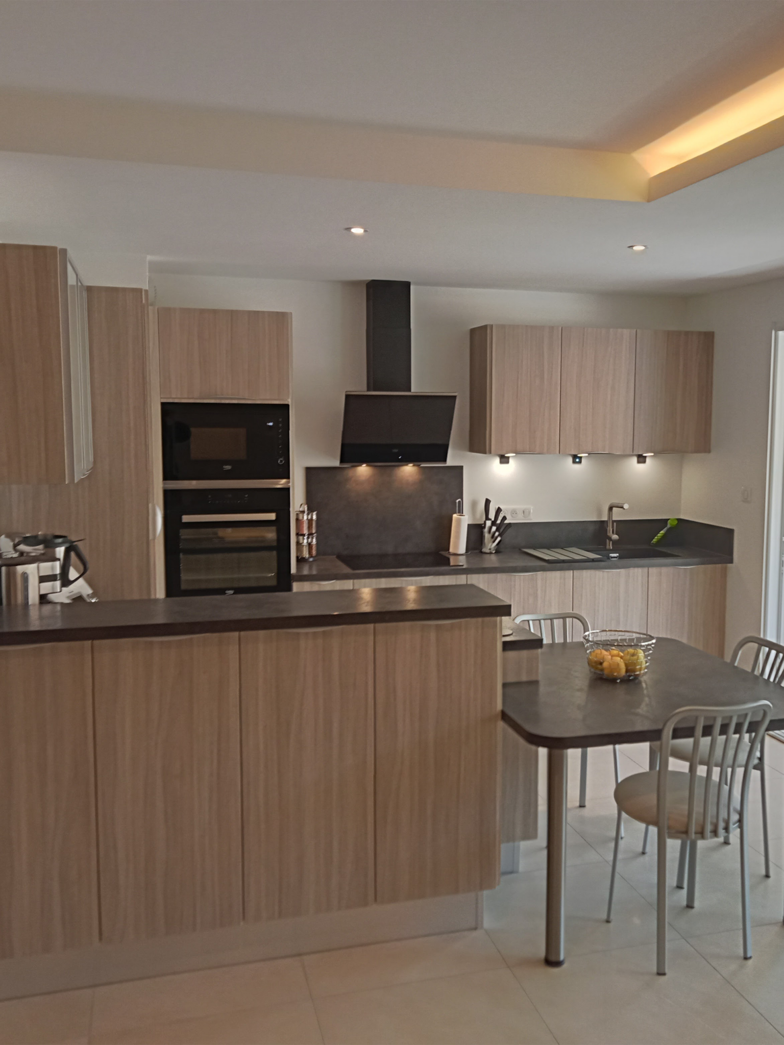 Cuisine moderne en bois clair et noir avec îlot central et équipements encastrés – Design fonctionnel et contemporain.